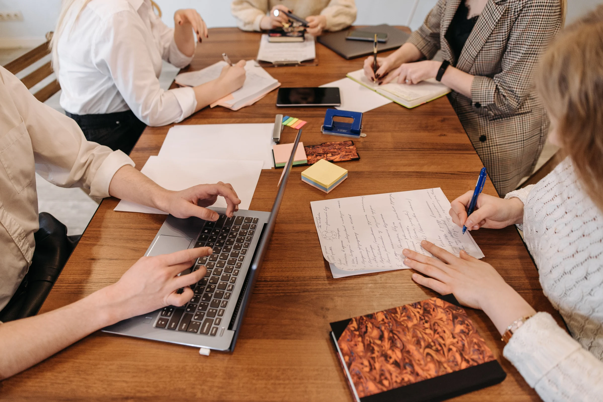 Fotografia documental de uma mesa de reunião com laptop, documentos e materiais de trabalho. — imagem 1 de 1.